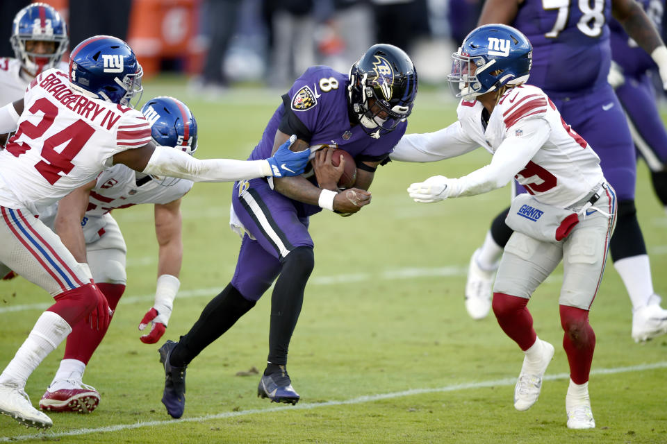 Baltimore Ravens quarterback Lamar Jackson (8) runs with the ball as New York Giants cornerback James Bradberry (24) and safety Xavier McKinney (29) try to stop him during the first half of an NFL football game, Sunday, Dec. 27, 2020, in Baltimore. (AP Photo/Gail Burton)