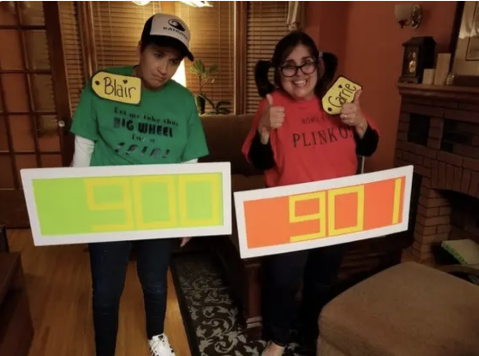 Two contestants with name tags and poster board on their front side with their opening bids