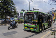 Conductor of an electric passenger bus calls to attract attention of the travelers in Kathmandu, Nepal, Wednesday, May 22, 2024. Nepal's abundant hydroelectric power is helping the Himalayan nation cut its oil imports and clean up its air, thanks to a boom in sales of electric vehicles. (AP Photo/Niranjan Shrestha)