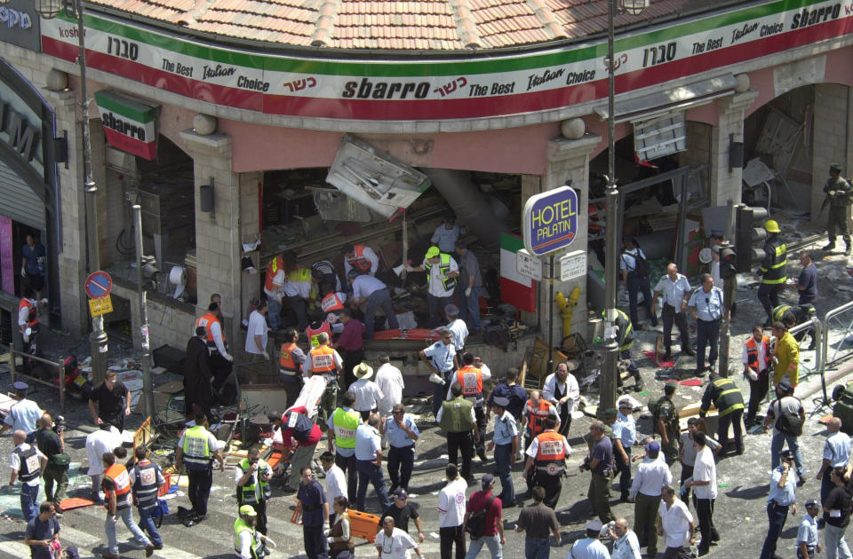Police and medics surround the scene of a bomb explosion in a restaurant downtown Jerusalem, Aug. 9, 2001. The family of an Israel-American girl killed in the 2001 Palestinian suicide bombing in Jerusalem is seeking a meeting with President Joe Biden in hopes of forcing Jordan to extradite a woman convicted in the deadly attack. The parents of Malki Roth sent a letter to the White House on Sunday, July 10, 2022 asking to meet with Biden when he comes to Jerusalem this week. They want the president to put pressure on Jordan, a close American ally, to send Ahlam Tamimi to the U.S. for trial. (AP Photo/Peter Dejong)
