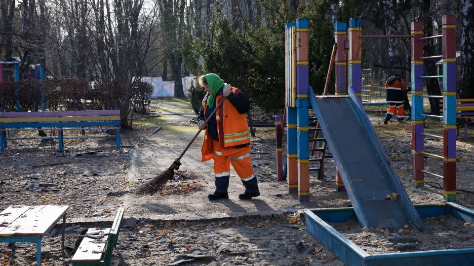 A municipal service worker sweeps up debris on the playground of a drone-damaged preschool in the Solomianskyi district of Kyiv, Ukraine, on November 25, 2023. - Global Images Ukraine/Global Images Ukraine/Getty Images