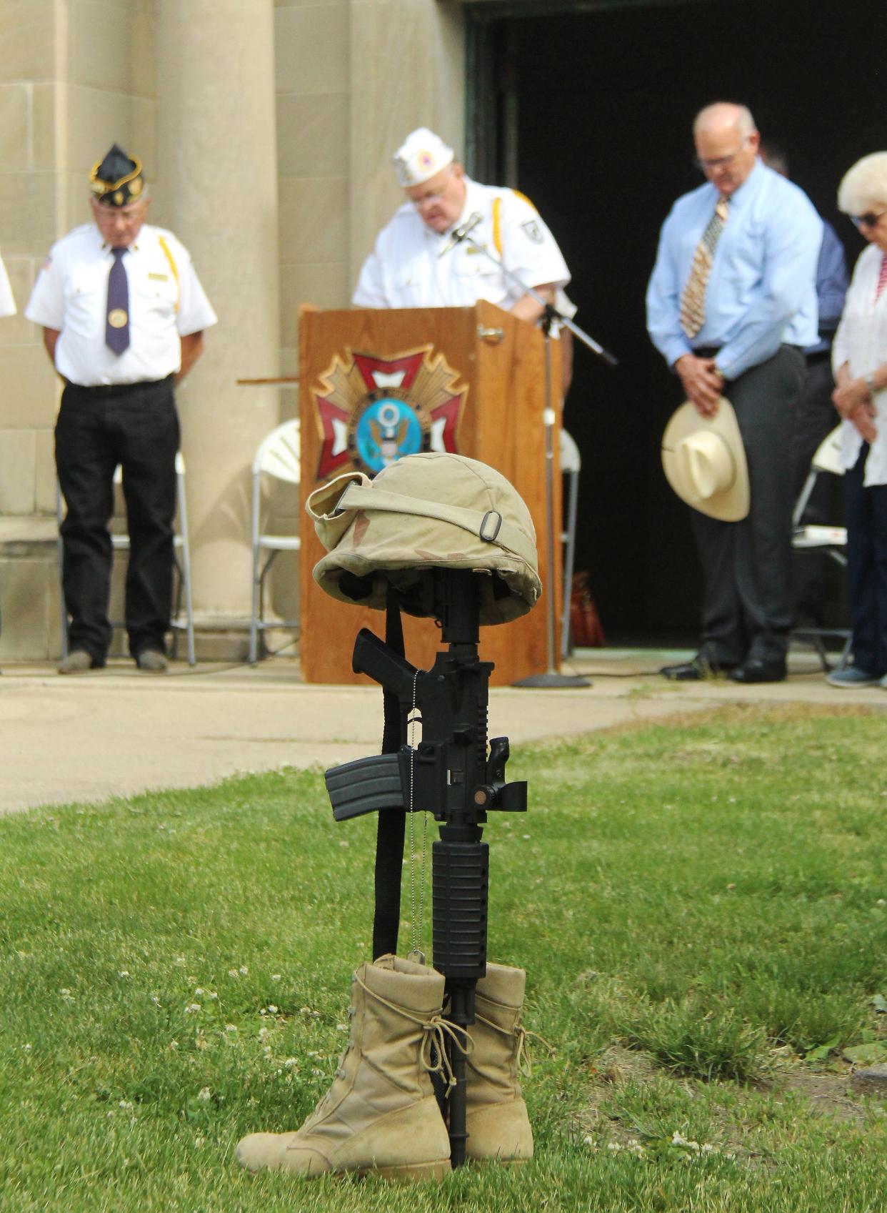 Terry Norgaard of the American Legion reads the POW Prayer behind the battle cross display during the Memorial Day service Monday at Southside Cemetery.