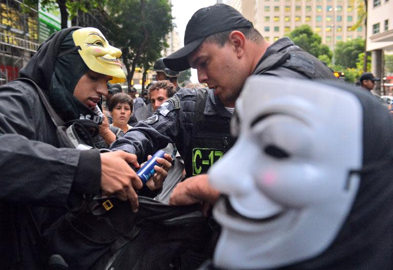Policemen look into the backpack of a man wearing a Guy Fawkes mask in Rio de Janeiro, Brazil on November 5, 2013