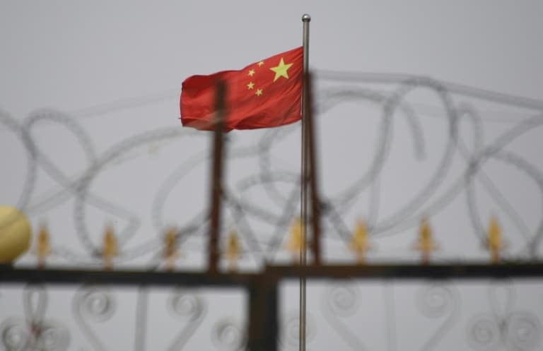 Le drapeau chinois flotte derrière des barbelés dans un complexe immobilier du Xinjiang, en Chine, en juin 2019  - GREG BAKER © 2019 AFP