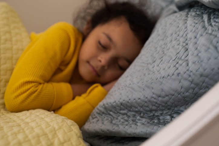 Child sleeping peacefully in bed, cuddled up in blankets