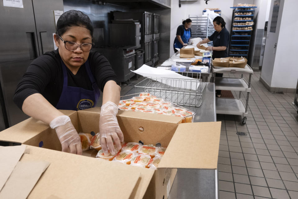 Firebaugh High School cafeteria worker Claudia Rodriguez prepares fruit cups for lunch in Lynwood, Calif. on Wednesday, April 3, 2024. Demand for school lunches has increased after California guaranteed free meals to all students regardless of their family's income. Now, districts are preparing to compete with the fast food industry for employees after a new law took effect guaranteeing a $20 minimum wage for fast food workers. (AP Photo/Richard Vogel)