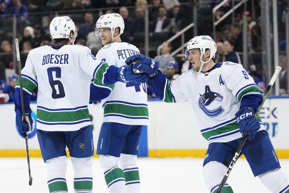 Vancouver Canucks' Elias Pettersson, center, celebrates with Brock Boeser, left, and J.T. Miller, right, after scoring scoring an empty-net goal during the third period of an NHL hockey game against the New York Rangers, Monday, Jan. 8, 2024, in New York. (AP Photo/Frank Franklin II)