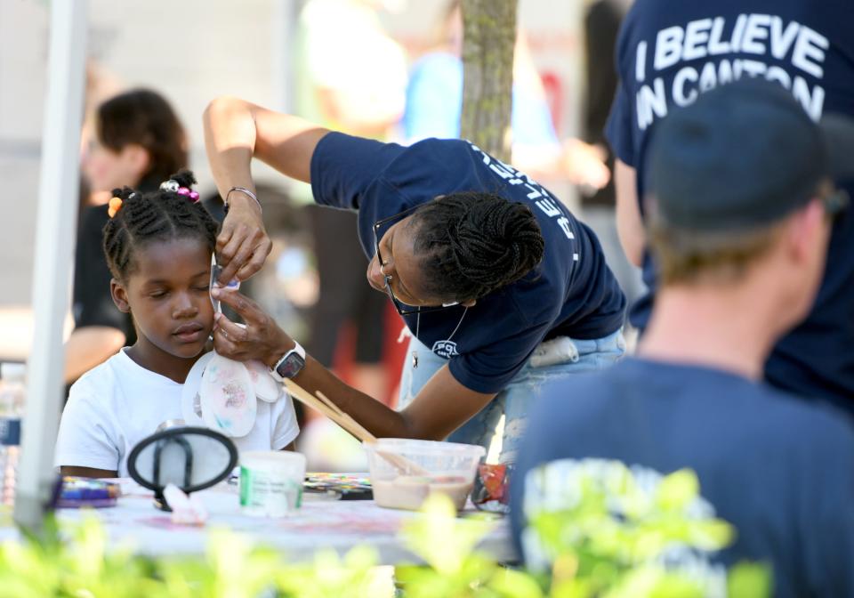 Canton police officer Aminata NDiaye paints the face of Jania Wilson, 9, of Canton during this year's first We Believe in Cantonon Wednesday at Centennial Plaza in Canton.