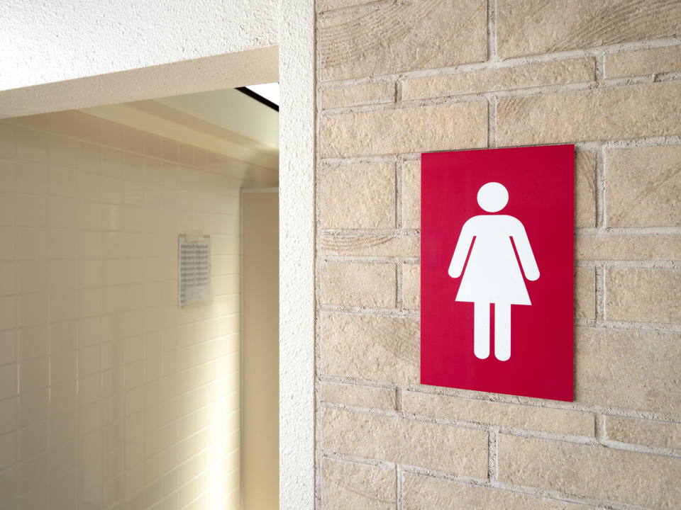 Women's restroom sign on a brick wall next to a bathroom entrance