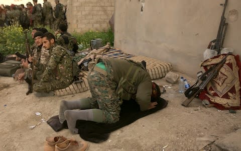 A US-backed Syrian Democratic Forces (SDF) fighter prays after returning from the front line in their fight against Islamic State militants in Baghouz, Syria - Credit: AP