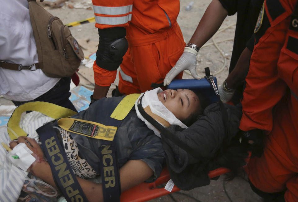 In this Sunday, Sept. 30, 2018, file photo, rescuers carry an earthquake survivor at restaurant building damaged by a massive earthquake and a tsunami in Palu, Central Sulawesi, Indonesia. (AP Photo/Tatan Syuflana, File)