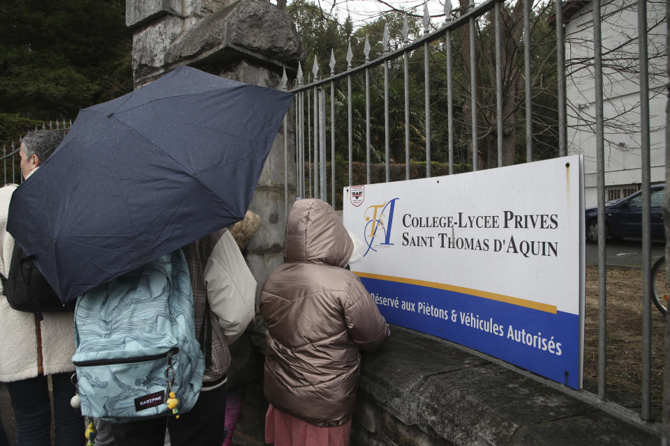 A child looks through the entrance of a private Catholic school after a teacher has been stabbed to death by a high school student, Wednesday, Feb. 22, 2023 in Saint-Jean-de-Luz, southwestern France. The student has been arrested by police, the prosecutor of Bayonne said. (AP Photo/Bob Edme)