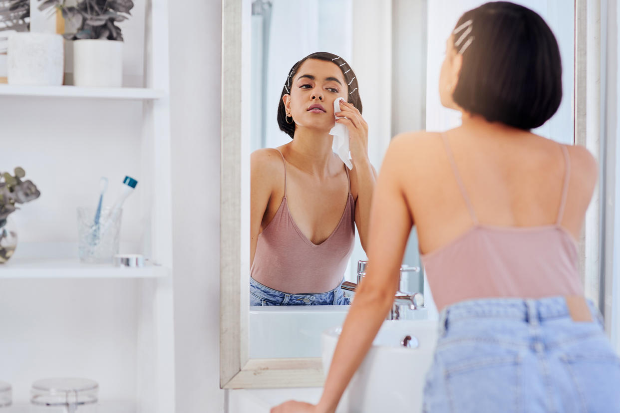 Shot of an attractive young woman cleansing her face with a wipe in front of the bathroom mirror
