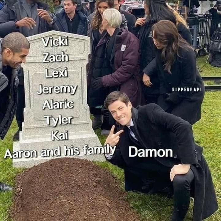 A man makes a V sign and poses in front of someone's grave