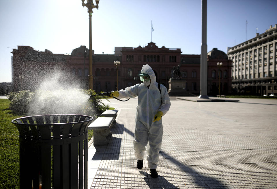 Un hombre rocía lejía en la Plaza de Mayo en Buenos Aires, Argentina, el viernes 20 de marzo de 2020. El gobierno de Argentina impuso una cuarentena nacional obligatoria para contener la propagación del coronavirus. (AP Foto / Natacha Pisarenko)