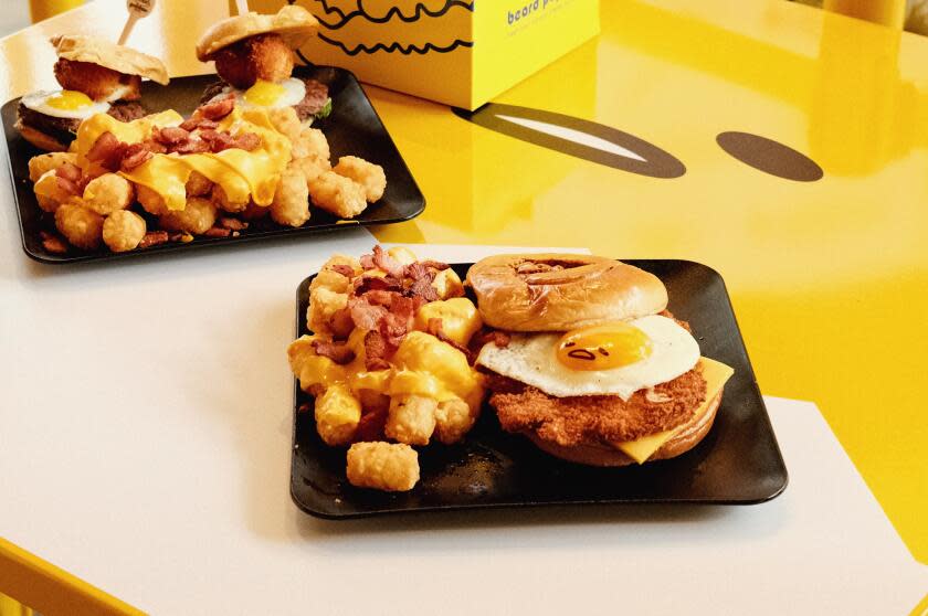 An egg-topped katsu sandwich and egg-topped sliders both with tots on a Gudetama table at The Gudetama Cafe in Buena Park