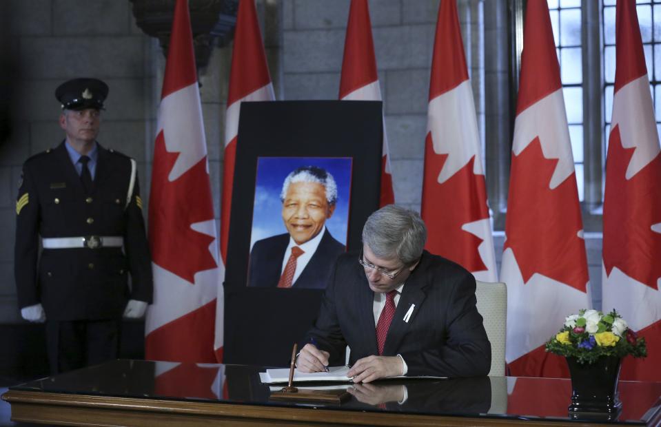 Canada's Prime Minister Stephen Harper signs a book of condolence for former South African President Nelson Mandela on Parliament Hill in Ottawa December 6, 2013. REUTERS/Chris Wattie (CANADA - Tags: POLITICS OBITUARY)