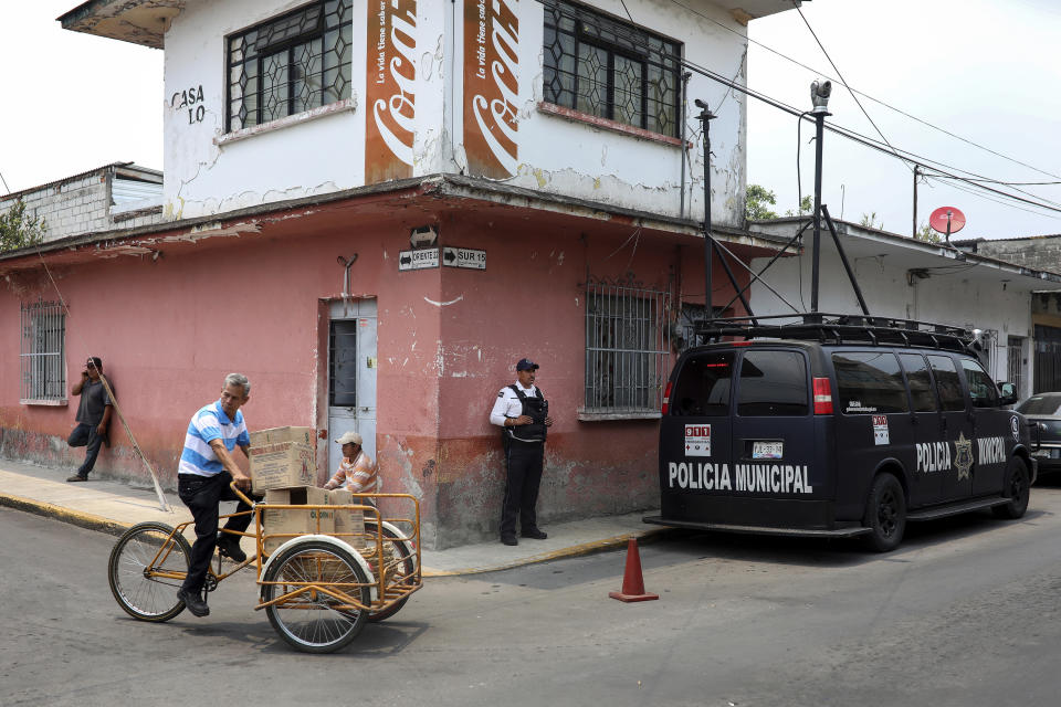 A municipal police officer stands guard on the corner of the street where the forensic office is located, where the bodies of Mixtla de Altamirano Mayor Maricela Vallejo, her husband and her driver were taken in Orizaba, Veracruz, Mexico, Thursday, April 25, 2019. Prosecutors said the three came under fire from behind and both sides of their SUV while traveling on a highway. (AP Photo/Felix Marquez)