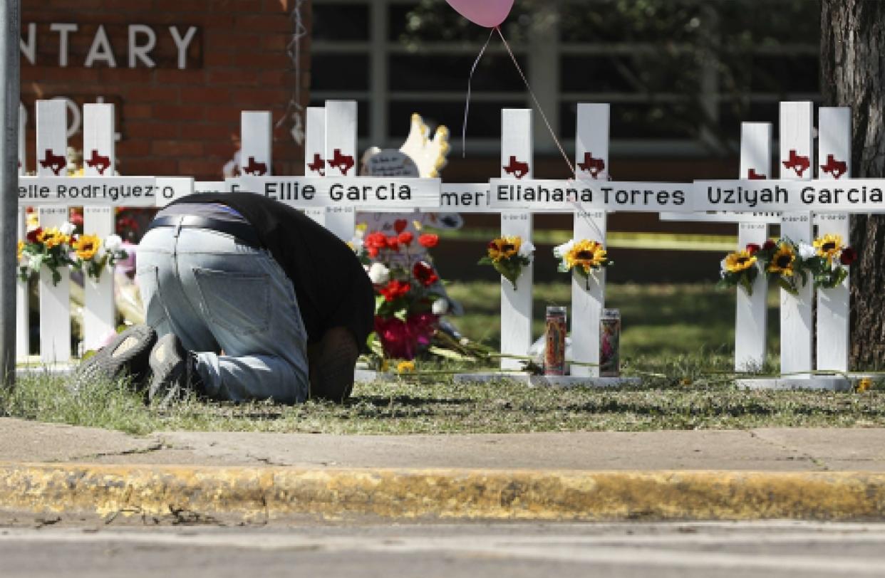 A mourner bows down in prayer at a memorial site for the victims of the Robb Elementary School shooting, Thursday, May 26, 2022, in Uvalde, Texas. 