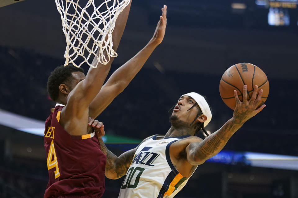 Utah Jazz's Jordan Clarkson (00) drives to the basket again Cleveland Cavaliers' Evan Mobley (4) in the first half of an NBA basketball game, Sunday, Dec. 5, 2021, in Cleveland. (AP Photo/Tony Dejak)