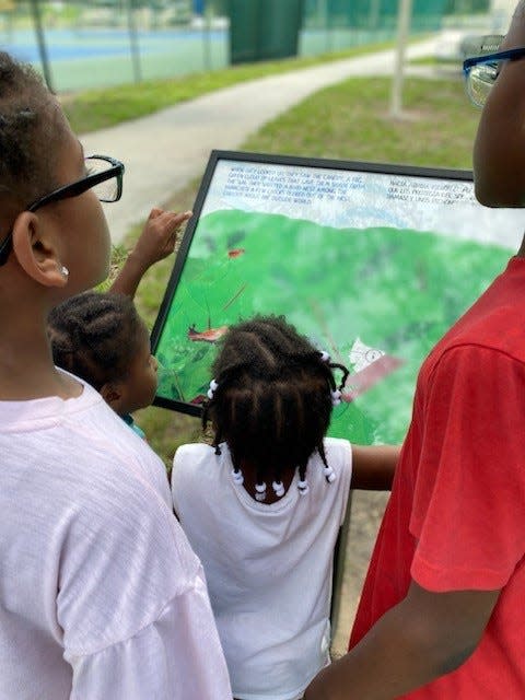 Children read a picture book at the new Book Walk in Lehigh Acres' Veterans Park.