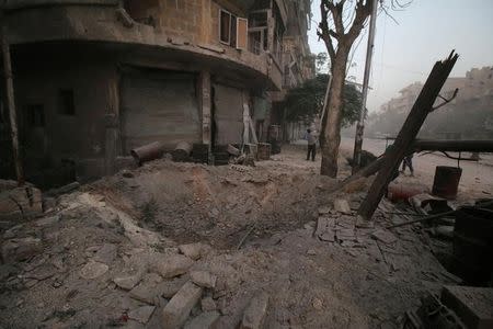 A man inspects damage near a hole in the ground after airstrikes on the rebel held al-Ansari neighborhood of Aleppo. REUTERS/Abdalrhman Ismail