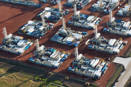 Stacked rigs are seen along with other idled oil drilling equipment at a depot in Dickinson, North Dakota June 26, 2015. REUTERS/Andrew Cullen