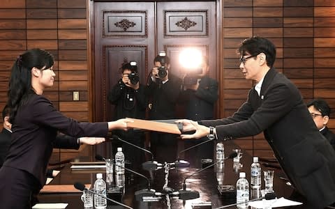 North Korean Hyon Song Wol, left, head of a North Korean art troupe, exchanges documents with her South Korean counterpart Yun Sang after a meeting at the North side of Panmunjom last week