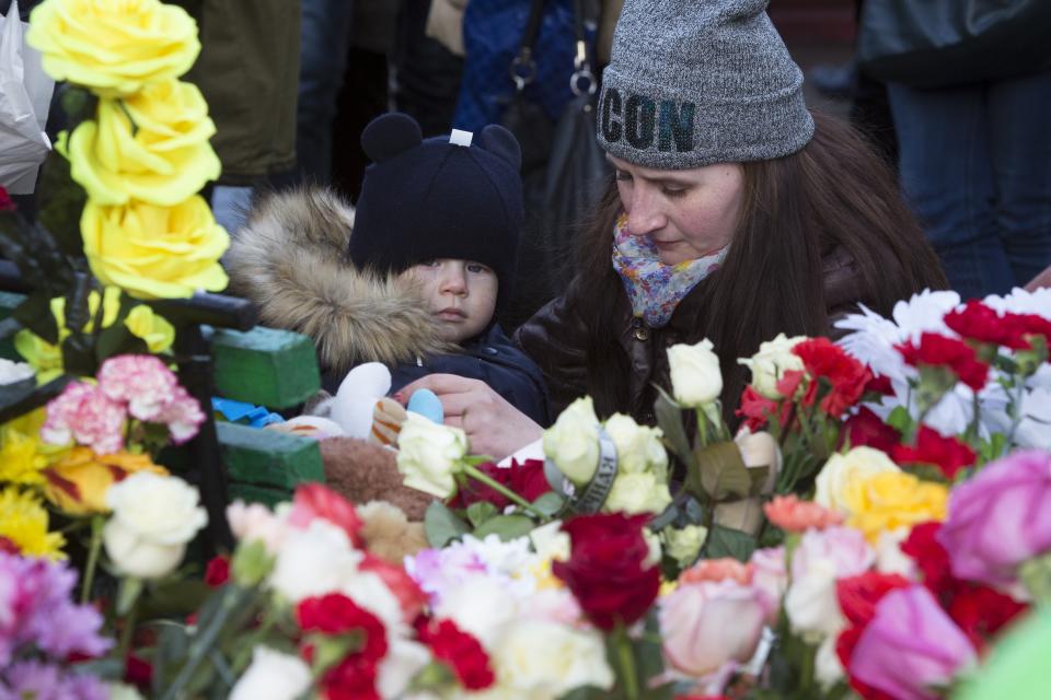 A woman with her child lays flowers for the victims