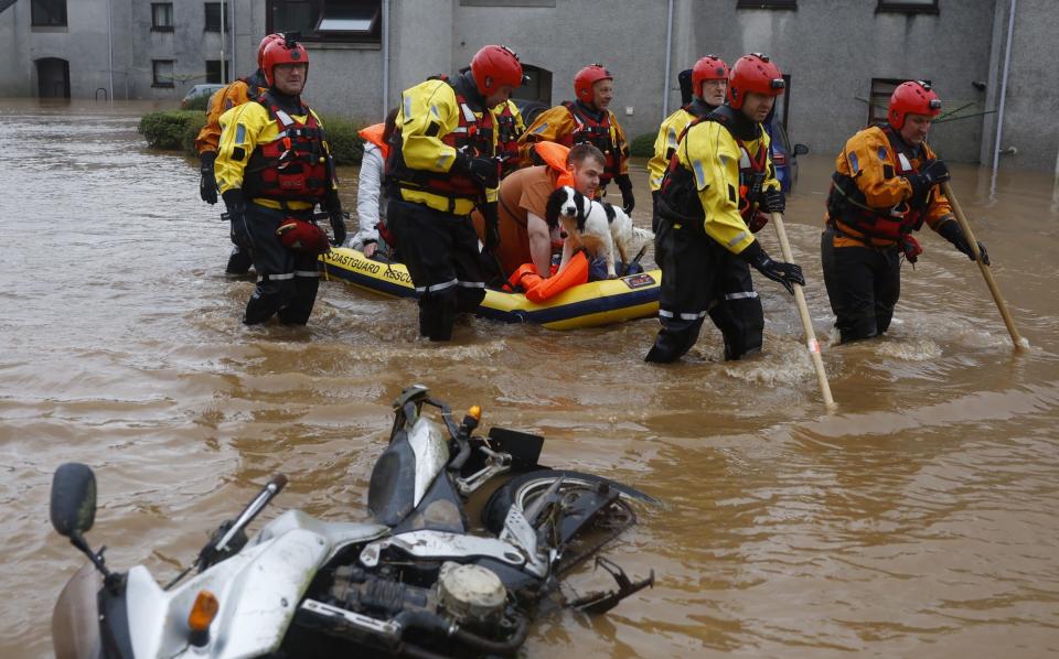 Members of the coastguard rescue team wade through the flood waters to evacuate a man and a dog on October 20, 2023 in Brechin, Scotland