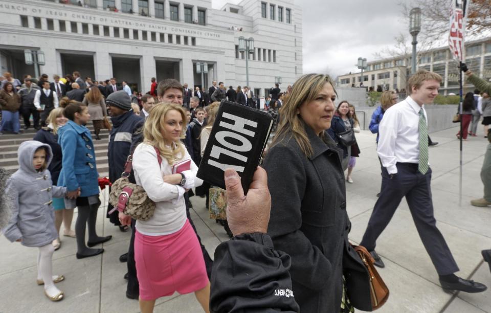 People walk pass a unidentified protester with a bible on their way from the Conference Center during opening session of the two-day Mormon church conference Saturday, April 5, 2014, in Salt Lake City. More than 100,000 Latter-day Saints are expected in Salt Lake City this weekend for the church's biannual general conference. Leaders of The Church of Jesus Christ of Latter-day Saints give carefully crafted speeches aimed at providing members with guidance and inspiration in five sessions that span Saturday and Sunday. They also make announcements about church statistics, new temples or initiatives. In addition to those filling up the 21,000-seat conference center during the sessions, thousands more listen or watch around the world in 95 languages on television, radio, satellite and Internet broadcasts. (AP Photo/Rick Bowmer)