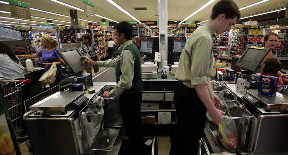 Employees ring through customers' purchases at the checkout counter at a Woolworths in Melbourne.