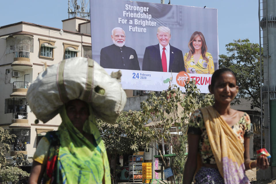 FILE - In this Feb. 18, 2020, file photo, Indian women walk past a hoarding showing Indian Prime Minister Narendra Modi, President Donald Trump and first lady Melania Trump to welcome them ahead of their visit to Ahmadabad, India. Trump is scheduled to visit the city during his Feb. 24-25 India trip. American dairy farmers, distillers and drug makers have been eager to break into India, the world’s seventh-biggest economy but a tough-to-penetrate colossus of 1.3 billion people. Looks like they’ll have to wait. Talks between the Trump administration and New Delhi, intended to forge at least a modest deal in time for President Donald Trump’s visit there, appear to have fizzled. Barring some last-minute dramatics — always possible with the Trump White House — a U.S.-India trade pact is months away, if not longer. For now, the failure to reach an accord may reflect not so much the differences between Trump and Prime Minister Narendra Modi as the similarities. (AP Photo/Ajit Solanki, File)