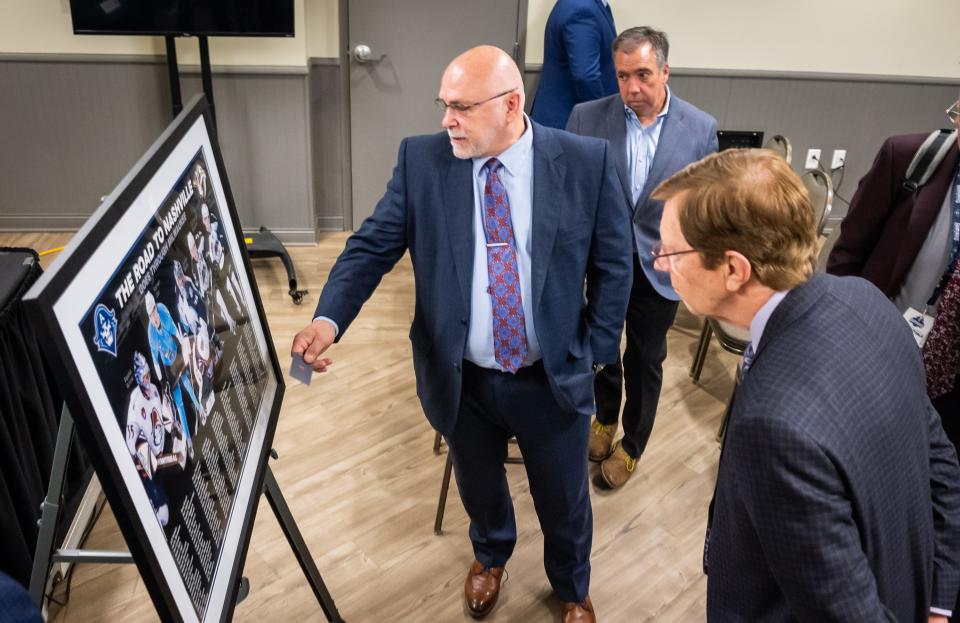Outgoing Nashville Predators general manager David Poile, right, and his successor, Barry Trotz, look over a piece of art detailing the 172 players who’ve skated for the Predators and the Milwaukee Admirals during the organizations’ affiliation.