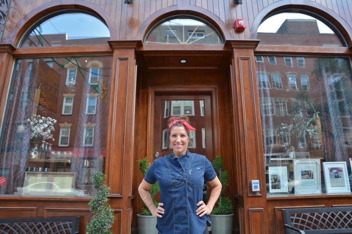 Jen Royle standing in front of Table's entrance with hands on hips, smiling, wearing a denim dress and red headband