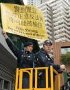 A policeman holds a sign as they watch a protest by pro-democracy activists during the Hong Kong chief executive election