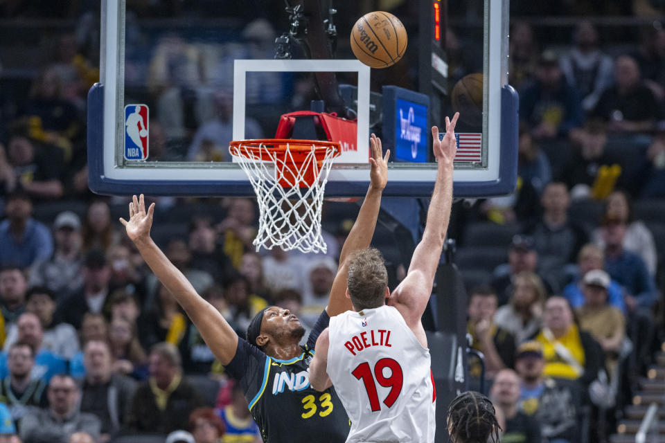 Toronto Raptors center Jakob Poeltl (19) shoots over the defense of Indiana Pacers center Myles Turner (33) during the first half of an NBA basketball game in Indianapolis, Monday, Feb. 26, 2024. (AP Photo/Doug McSchooler)