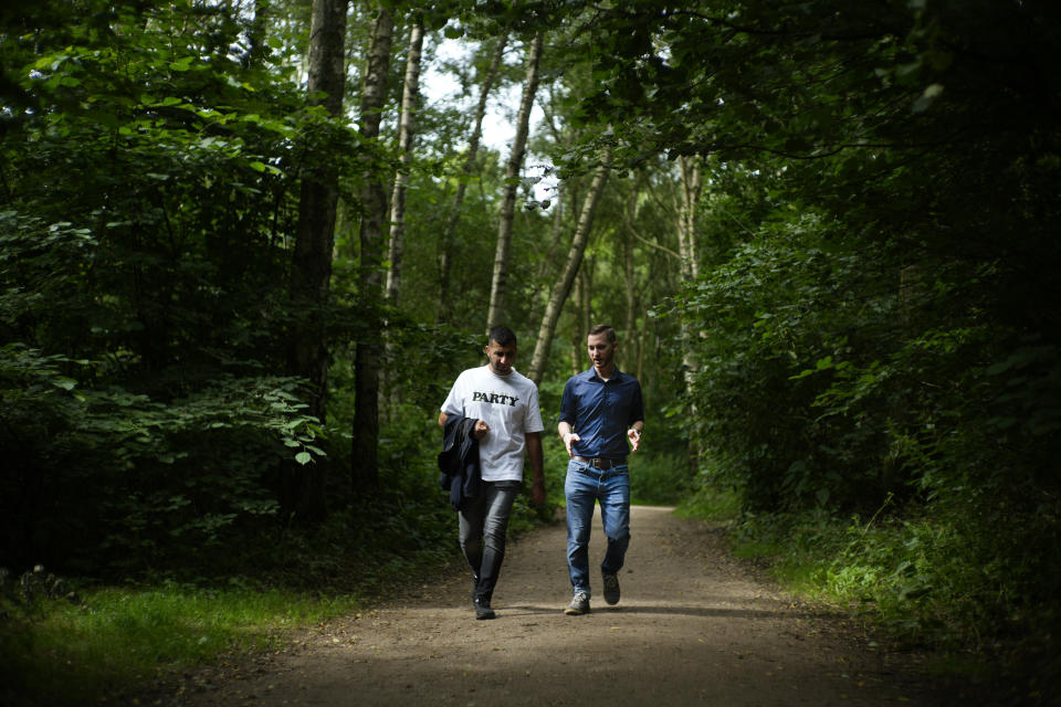 FILE - In this Aug. 14, 2021 file photo U.S. Army veteran Spencer Sullivan, right, and Abdulhaq Sodais, who served as a translator in Afghanistan, walk in a park in Bremen, Germany. Sullivan spent years fighting to get Sodais asylum after he risked his life aiding U.S. troops in Afghanistan during its 20-year war there and then was denied a U.S. visa. On Wednesday, Sept. 22, 2021, a German court granted Sodais asylum. (AP Photo/Peter Dejong,File)