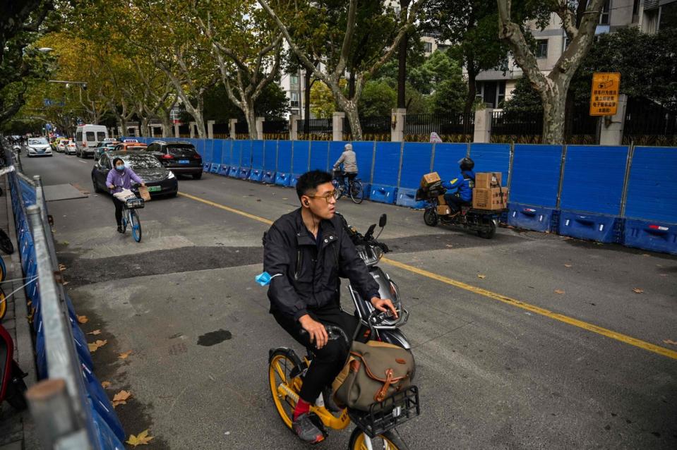 People ride bicycles next to barricades on Wulumuqi street, named for Urumqi in Mandarin, in Shanghai (AFP via Getty Images)