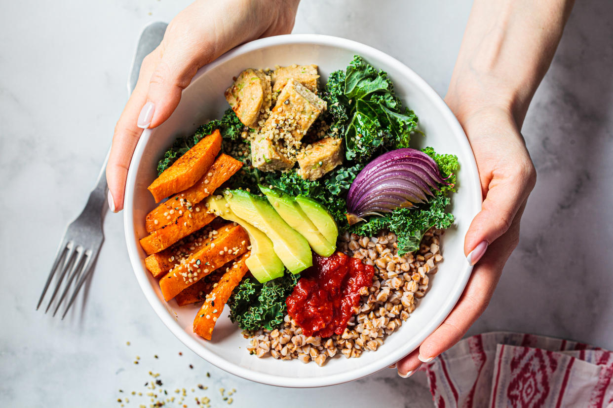 Woman holding vegan bowl of food (Getty Images)