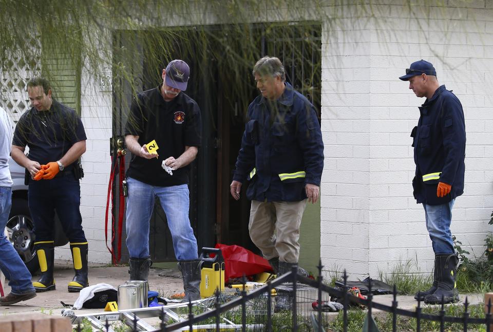 Phoenix Fire Department investigators look through evidence at a home where skeletal remains were found Wednesday, Jan. 29, 2020, in Phoenix. The remains have been found at a house where authorities previously removed at least one child as part of a child abuse investigation in which both parents of that child were in custody, police said Wednesday. (AP Photo/Ross D. Franklin)