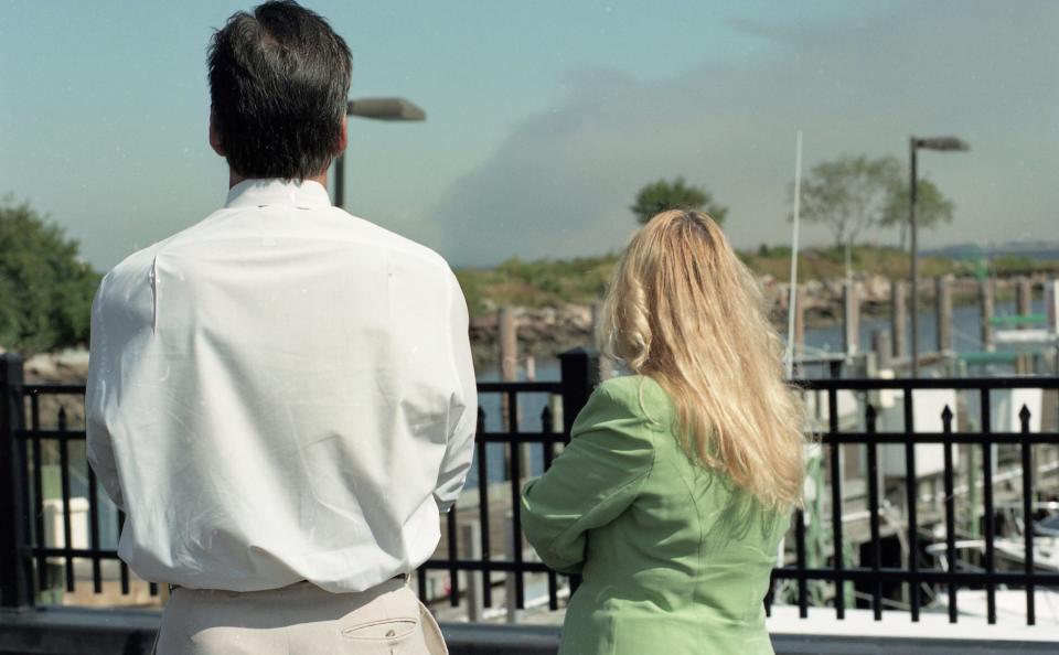 Unidentified bystanders at Atlantic Highlands Municipal Marina witness smoke rising from the World Trade Center in Lower Manhattan on September 11, 2001.