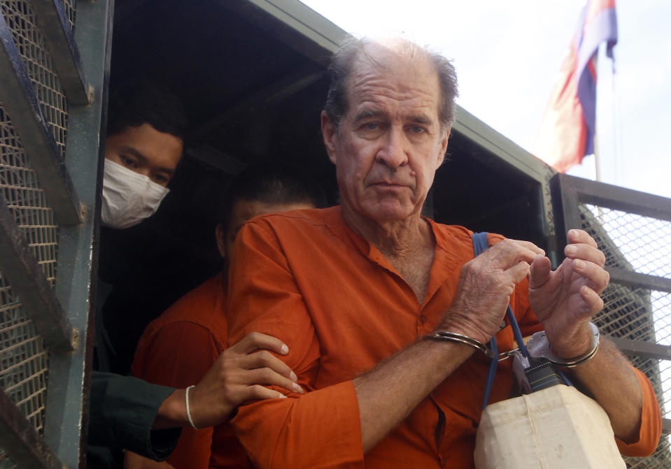 In this Aug. 29, 2018, file photo, Australian filmmaker James Ricketson, right, is helped off a prisoner truck upon his arrival at Phnom Penh Municipal Court in Phnom Penh, Cambodia. Ricketson is on trial in Cambodia on charges of endangering national security by flying a drone over an opposition party rally last year. Closing arguments in the trial are expected Wednesday. (AP Photo/Heng Sinith, File)