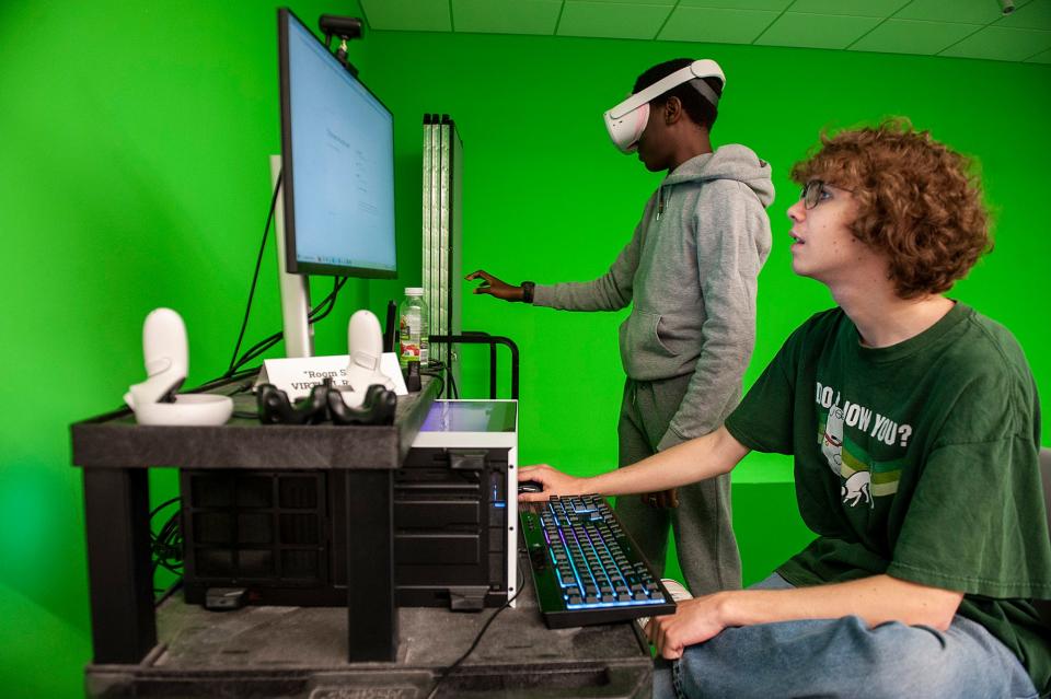 Kevin Kwasny, right, and Paul Bogere, wearing virtual reality headset, work on 3D modeling for a walkable city project while inside the digital storytelling space at New England Innovation Academy in Marlborough, April 30, 2024.