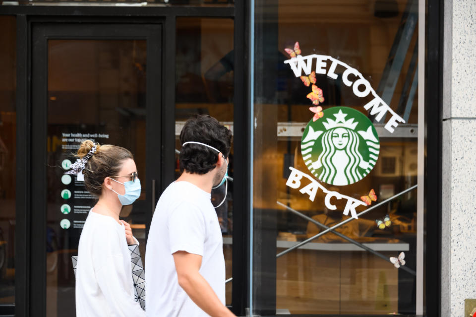 NEW YORK, NEW YORK - JUNE 23: People wear protective face masks outside Starbucks in midtown as the city moves into Phase 2 of re-opening following restrictions imposed to curb the coronavirus pandemic on June 23, 2020 in New York City. Phase 2 permits the reopening of offices, in-store retail, outdoor dining, barbers and beauty parlors and numerous other businesses. Phase 2 is the second of four-phased stages designated by the state. (Photo by Noam Galai/Getty Images)