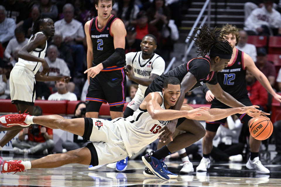 San Diego State forward Jaedon LeDee (13) and Boise State forward O'Mar Stanley scramble for the ball during the second half of an NCAA college basketball game Friday, March 8, 2024, in San Diego. (AP Photo/Denis Poroy)