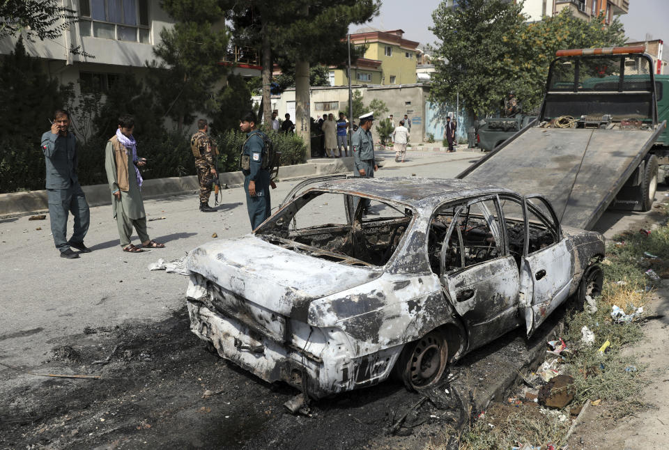 Security personnel inspect a damaged vehicle where rockets were fired from in Kabul, Afghanistan, Tuesday, July 20, 2021. At least three rockets hit near the presidential palace on Tuesday shortly before Afghan President Ashraf Ghani was to give an address to mark the Muslim holiday of Eid-al-Adha. (AP Photo/Rahmat Gul)