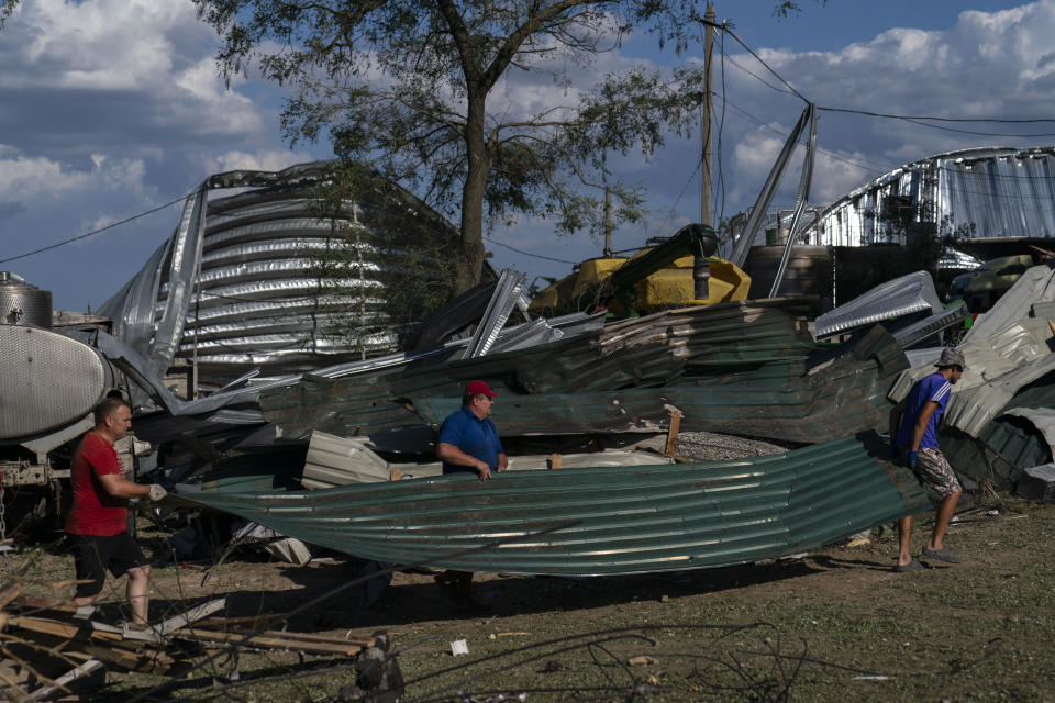 Workers carry a large piece of sheet metal from a destroyed warehouse at a grain facility in Pavlivka, Ukraine, Saturday, July 22, 2023, following Russian missile attacks. The collapse of the Black Sea grain deal and a series of missile strikes on Ukrainian grain silos and ports have left farmers with few options to export their grain. (AP Photo/Jae C. Hong)