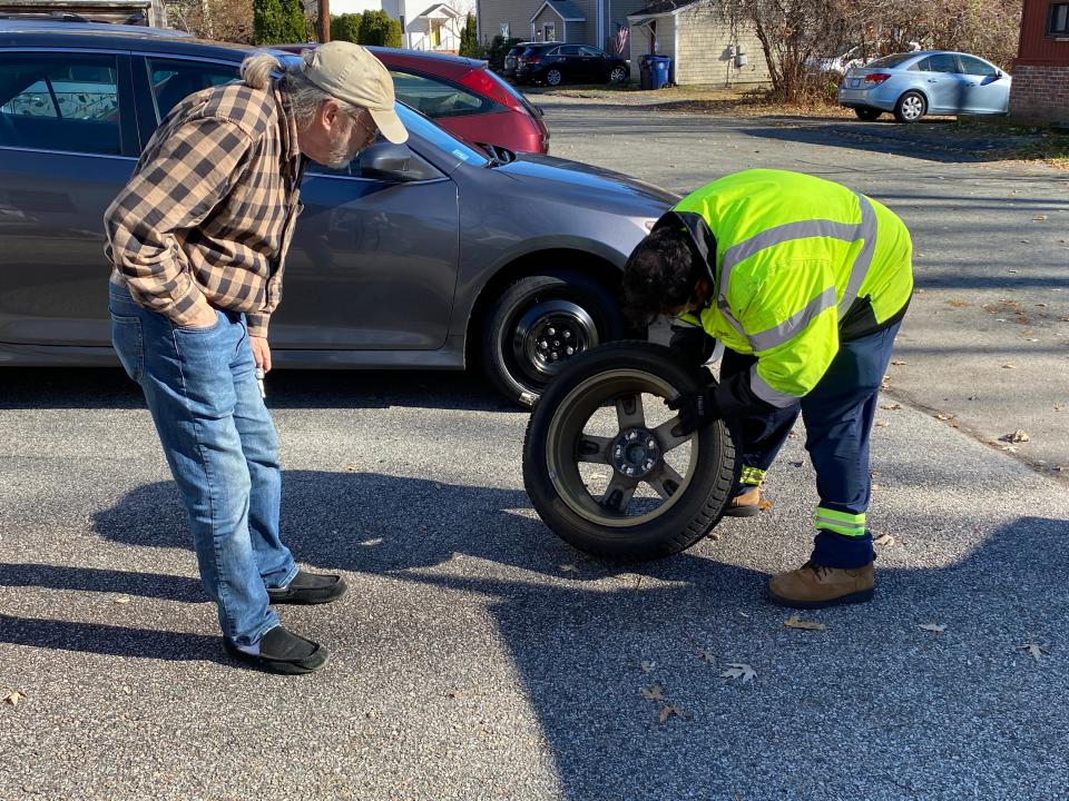 Jacob Viveiros changes a flat tire for 71-year-old Bob Hood in the Conimicut neighborhood of Warwick on Thanksgiving Day.