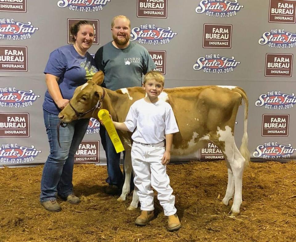 Ashley Bridges McMurry and her husband pose with their son, Charlie, and their cow at the 2019 N.C. State Fair.